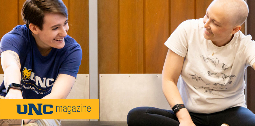 Two people stretching on the floor smiling at each other