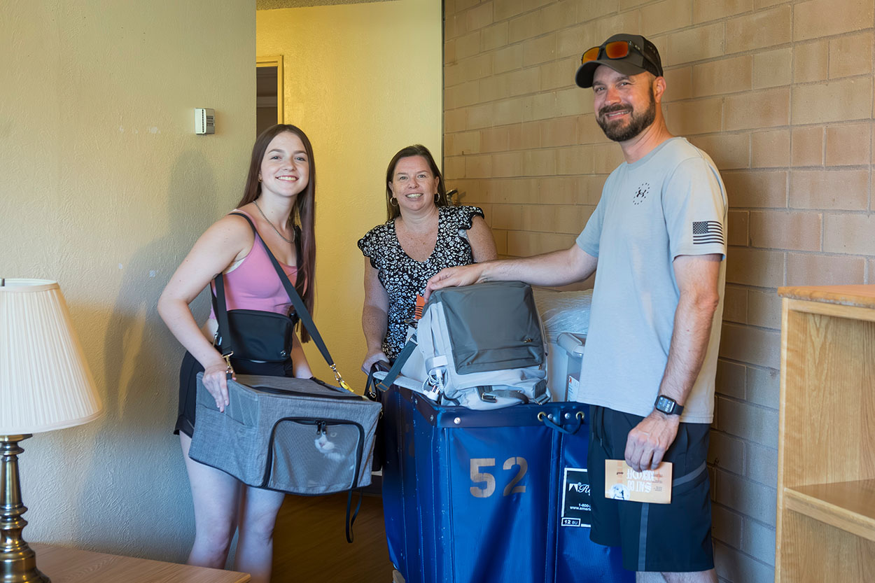 Family poses in their student's dorm room with luggage.