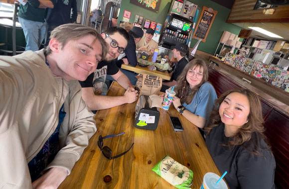 Selfie of four graduate students at table in restaurant.