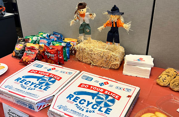 Pizzas, cookies and chips on a table with a miniature scarecrows and fall theme.