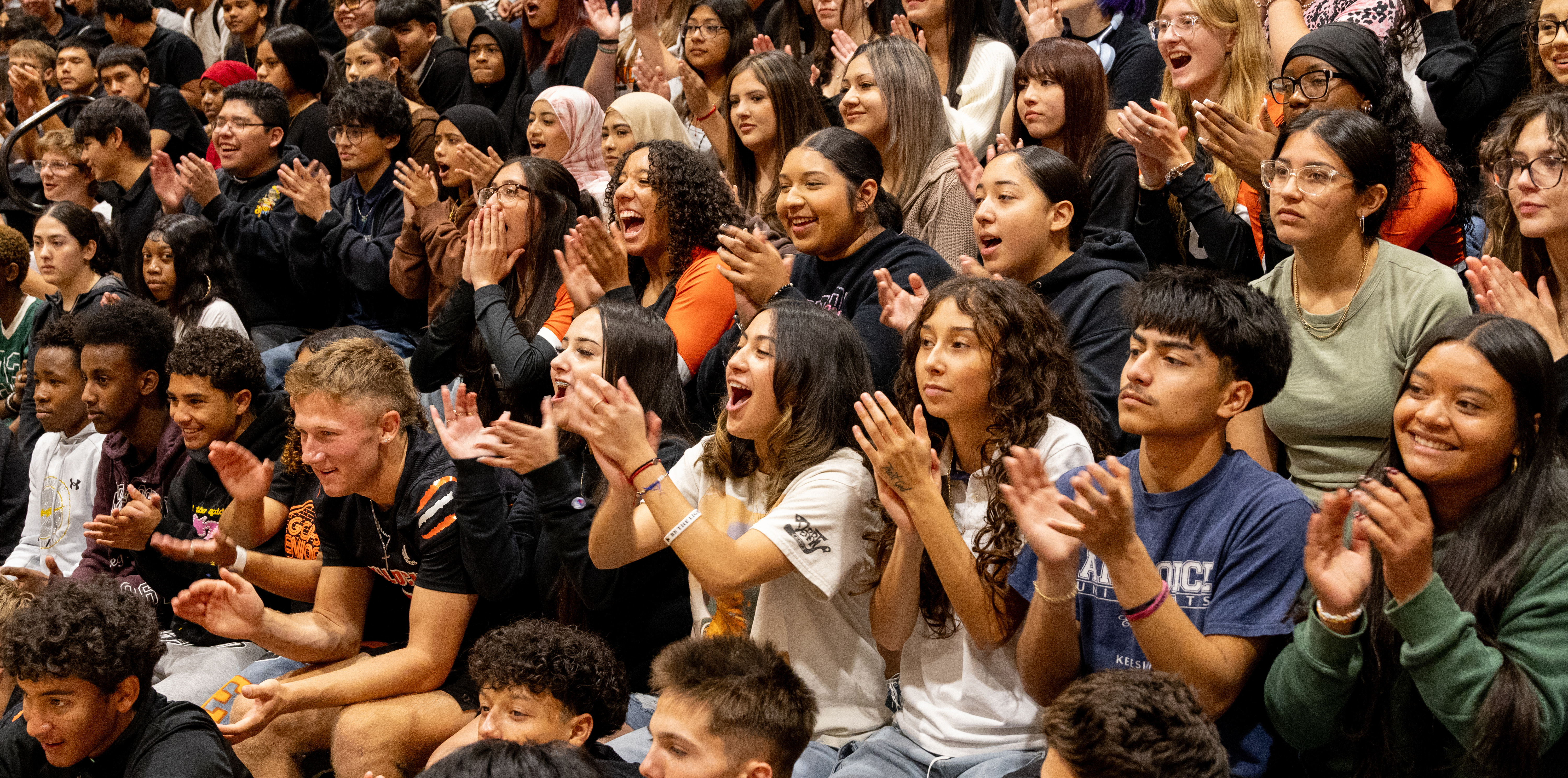 A high school crowd of students cheering on bleachers