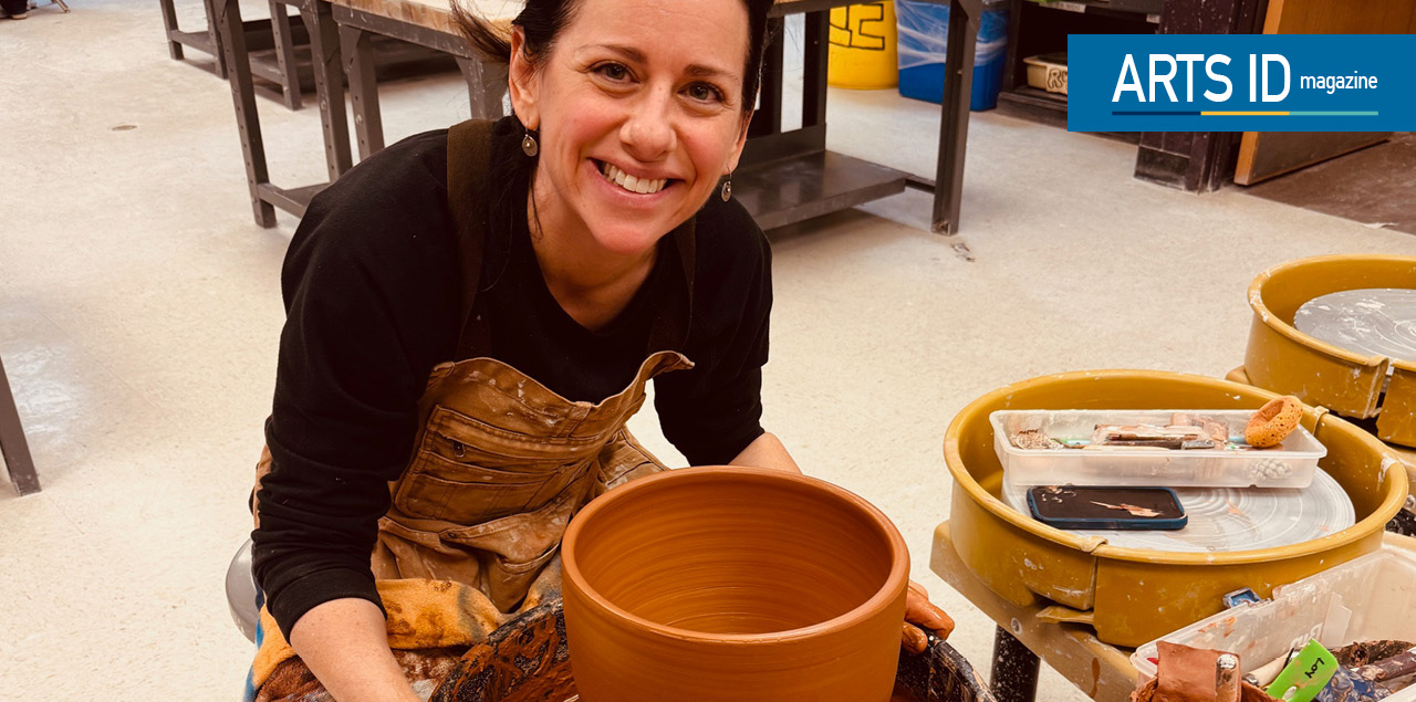 A woman smiling while sitting and making pottery