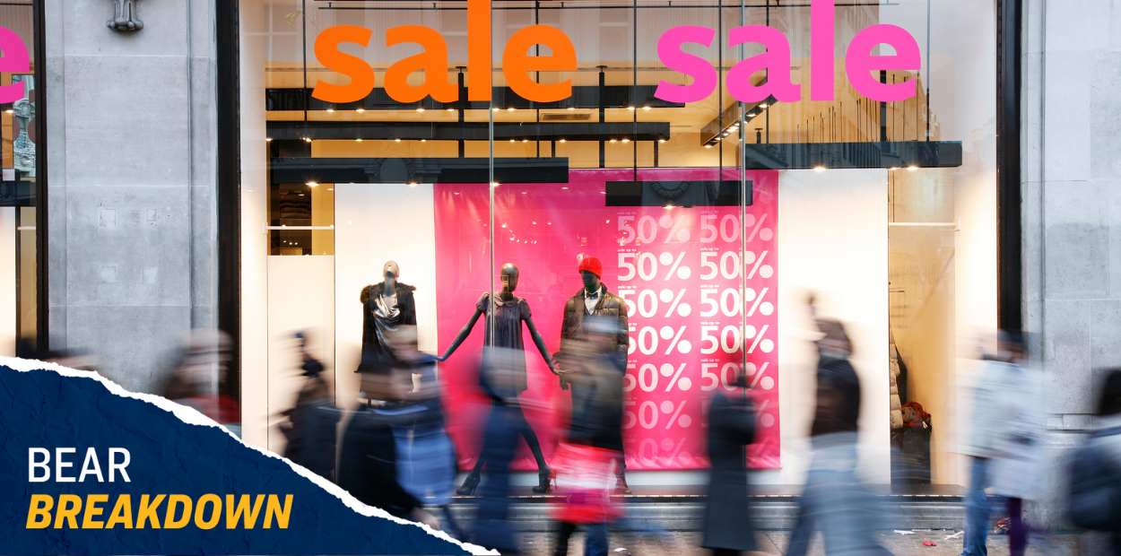 People walking by in a blur outside of a store window with "sale" signs hanging in it.