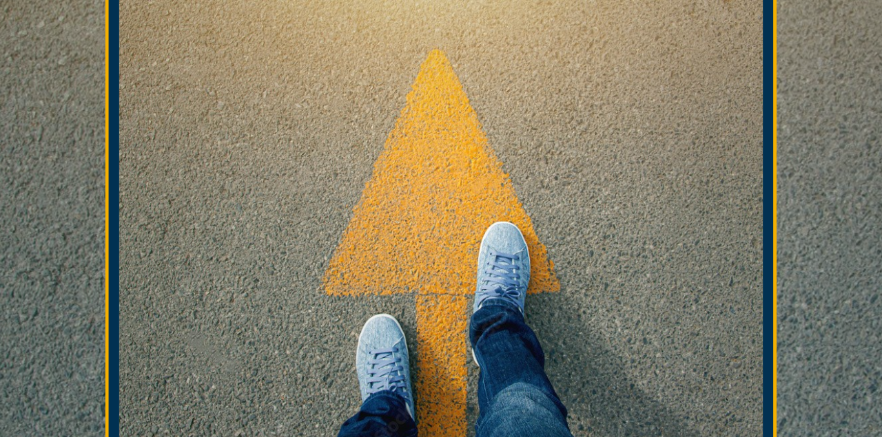 A child's feet standing on an arrow pointing forward on the street